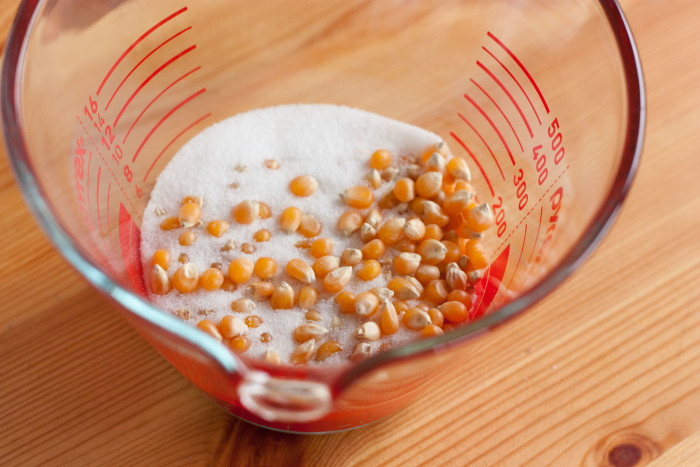 measuring cup with popcorn and sugar