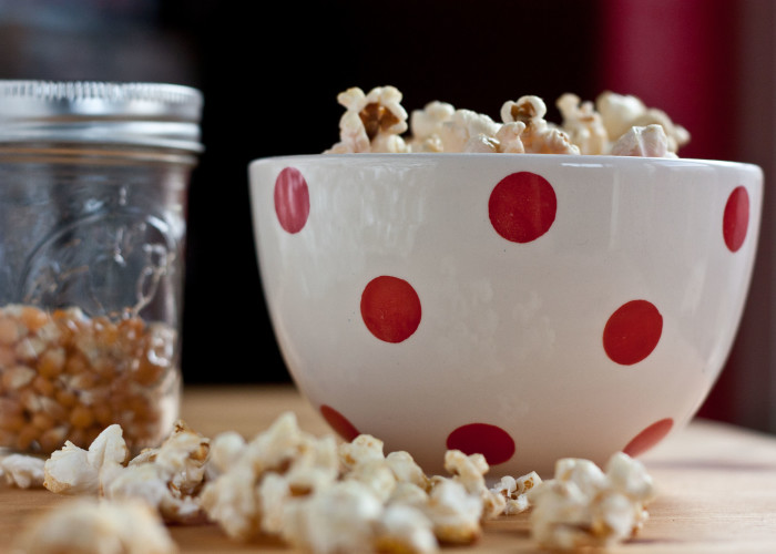 kettle corn in a polka dot bowl with popcorn spilled on the table