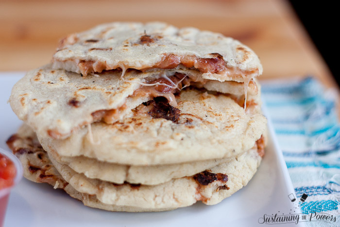 A stack of five pupusas with the filling showing.