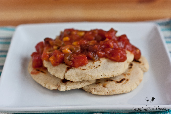 three pupusas with corn salsa on top.