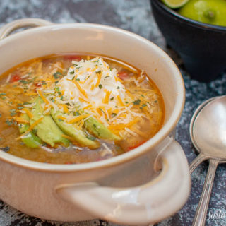 a bowl of tomatillo soup with avocado and sour cream