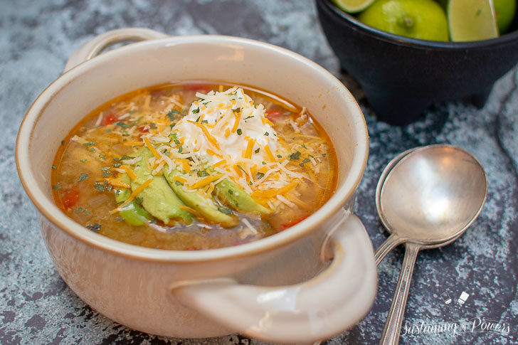 a bowl of tomatillo soup with avocado and sour cream