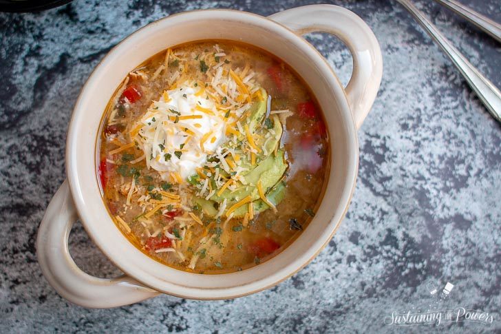 a bowl of tomatillo soup with avocado and sour cream