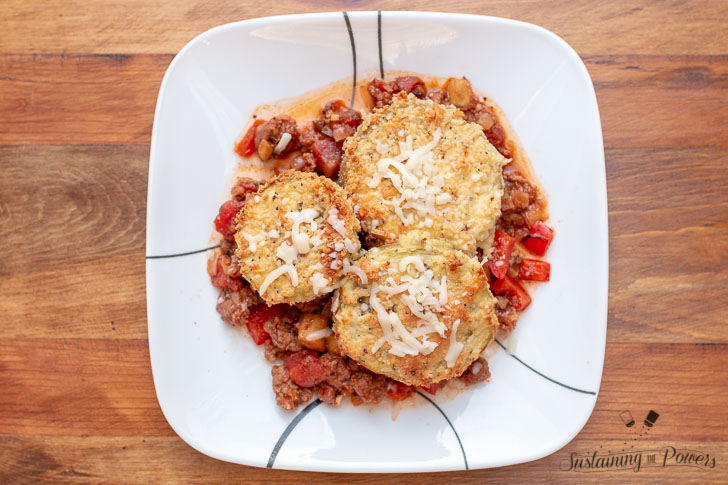 A plate with low-carb eggplant parmesan on top of meat sauce