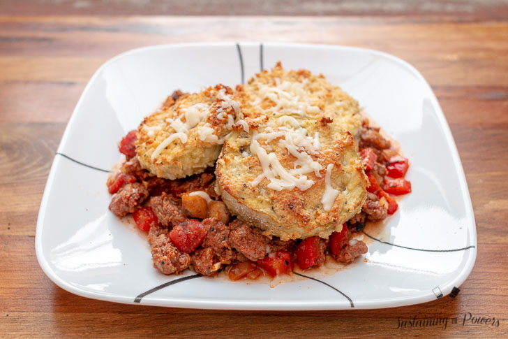 A plate of eggplant parmesan on top of a meat sauce