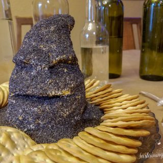 A cheese ball shaped like the sorting hat from Harry Potter, covered in poppy seeds and surrounded by crackers