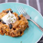 A plate on a table with a serving of keto taco bake casserole topped with sour cream.