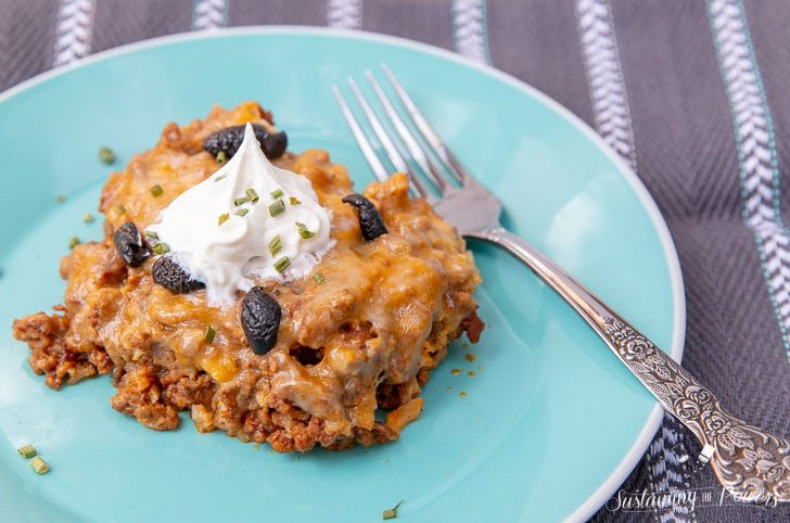 A plate on a table with a serving of keto taco bake casserole topped with sour cream.